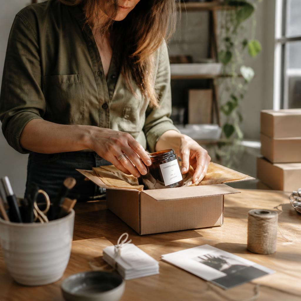 Small brand owner packing product orders in a sunlit studio